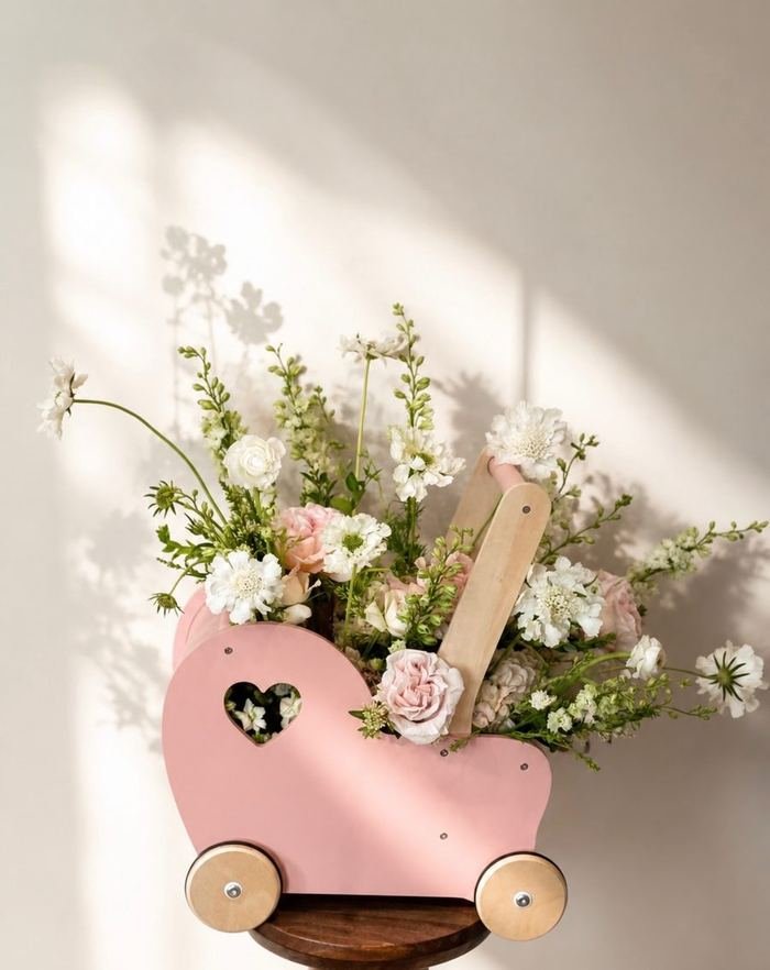 Pastel floral arrangement in a pink toy pram for a baby shower